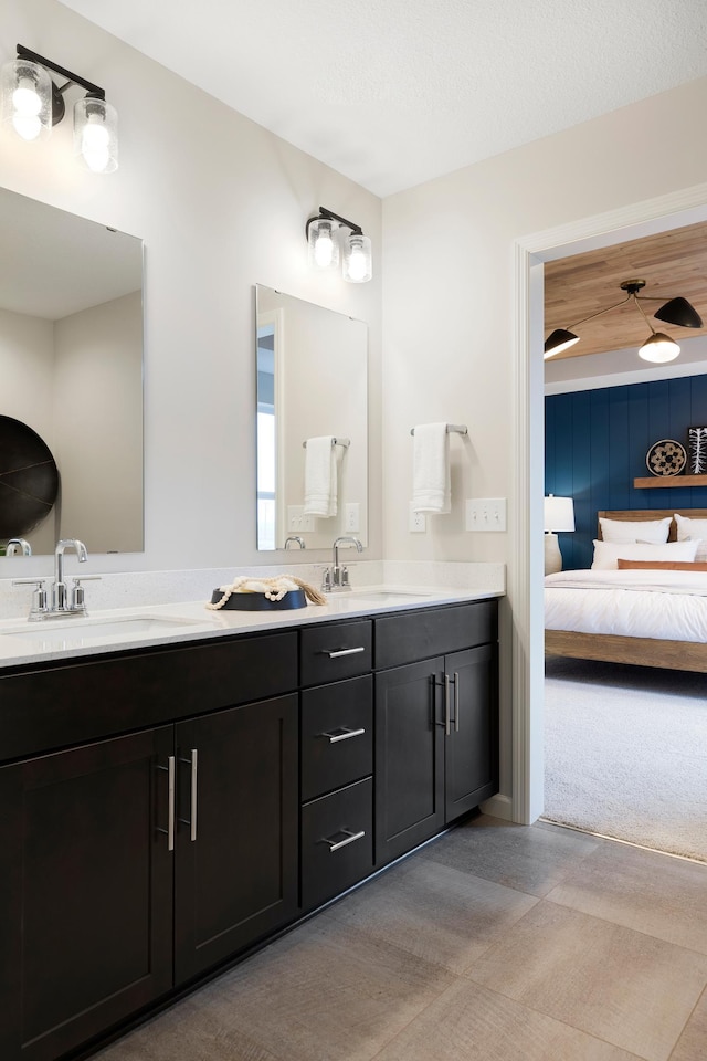 ensuite bathroom with double vanity, ensuite bath, and a sink