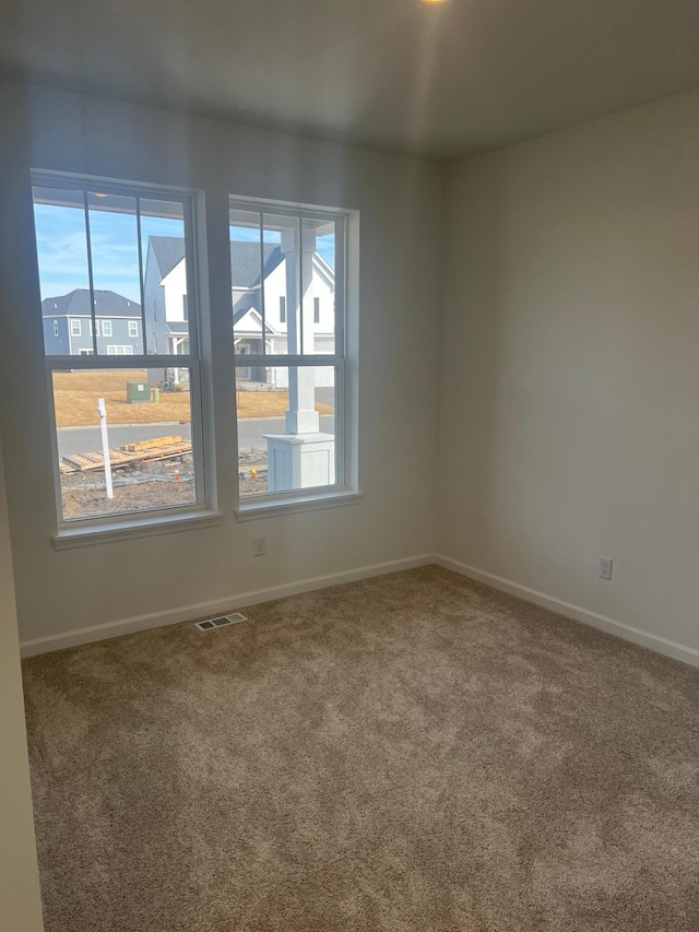 empty room with carpet flooring, baseboards, and visible vents