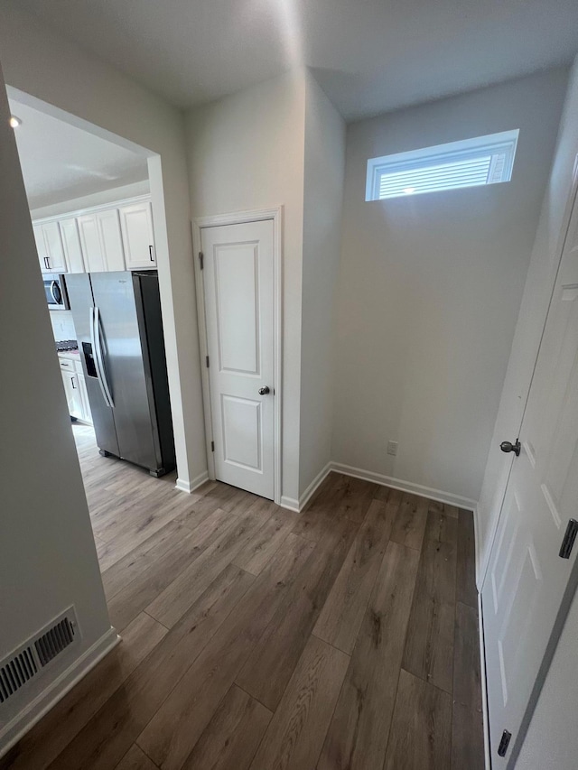 unfurnished dining area featuring visible vents, baseboards, and wood finished floors