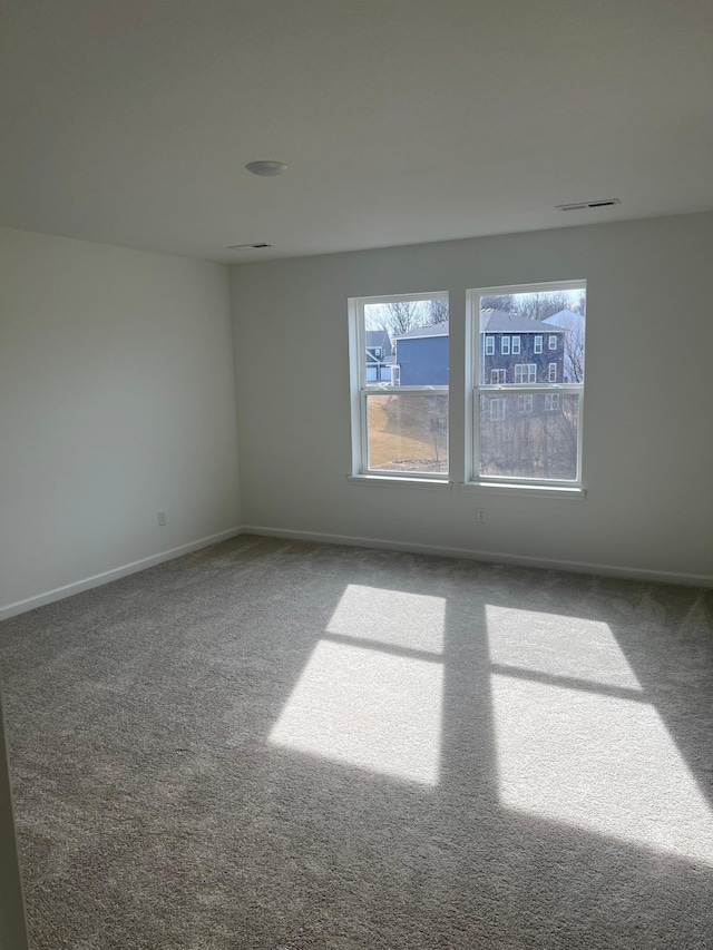 carpeted spare room with visible vents and baseboards