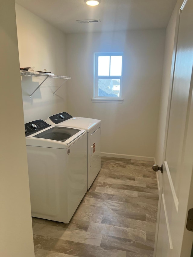 washroom with visible vents, independent washer and dryer, light wood-style flooring, baseboards, and laundry area