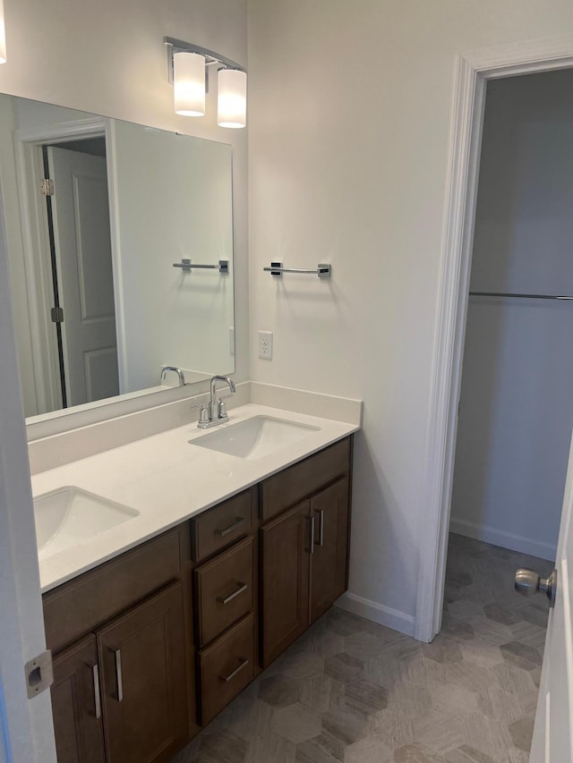 full bathroom featuring double vanity, baseboards, and a sink