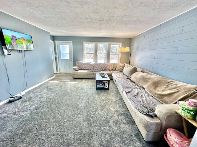 carpeted living area with wooden walls, baseboards, and a textured ceiling