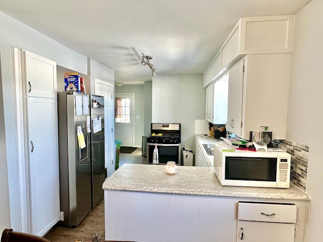 kitchen with light countertops, appliances with stainless steel finishes, a peninsula, and white cabinetry