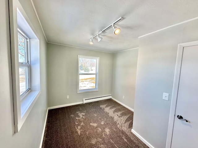 unfurnished room featuring carpet floors, track lighting, a baseboard radiator, and baseboards