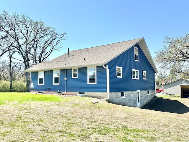 rear view of house featuring a lawn and roof with shingles