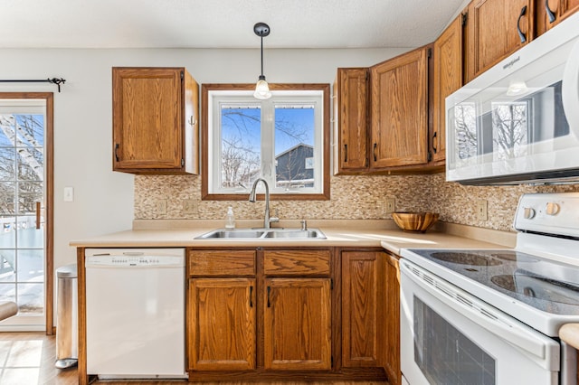 kitchen with a wealth of natural light, white appliances, brown cabinetry, and a sink