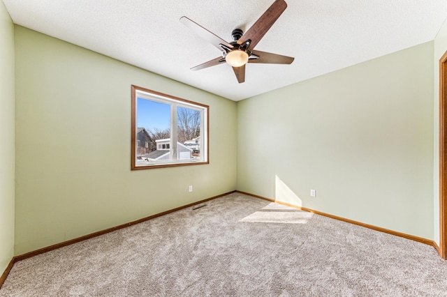 empty room with carpet flooring, a ceiling fan, baseboards, and a textured ceiling