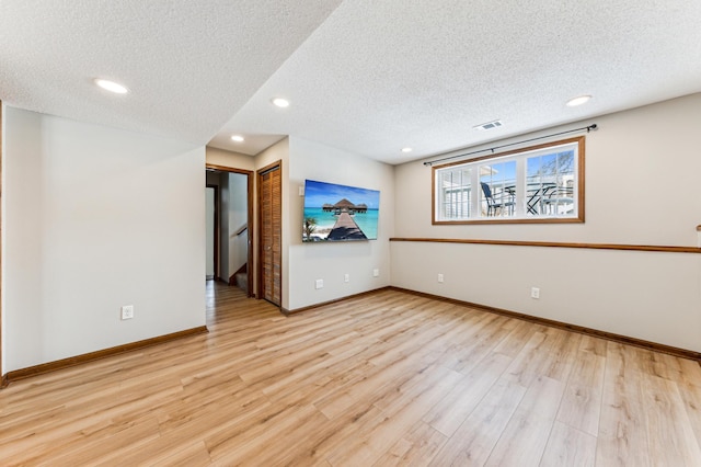 spare room featuring baseboards, visible vents, light wood-style flooring, recessed lighting, and a textured ceiling