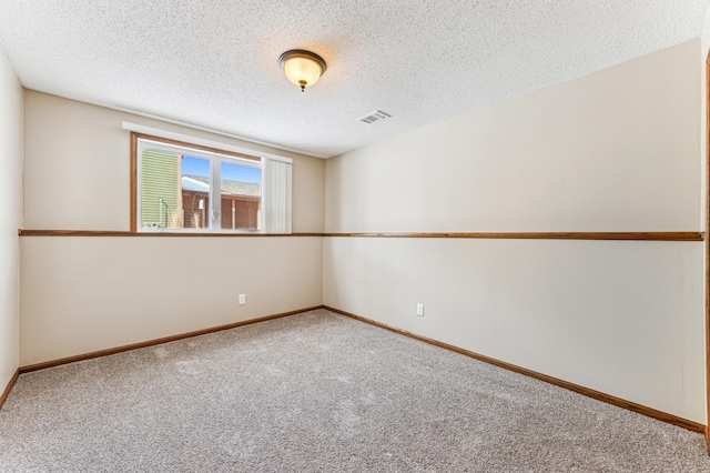 carpeted empty room featuring visible vents, a textured ceiling, and baseboards