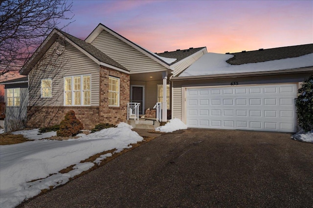 ranch-style house with aphalt driveway, a garage, and brick siding