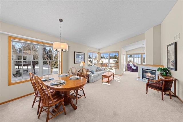 carpeted dining room with vaulted ceiling, baseboards, visible vents, and a premium fireplace