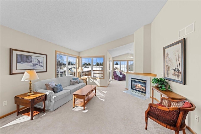 living area featuring visible vents, carpet floors, a fireplace with flush hearth, vaulted ceiling, and a textured ceiling