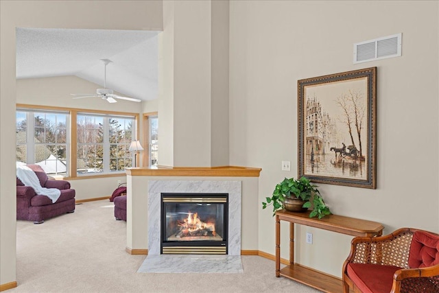 living area featuring visible vents, a high end fireplace, baseboards, carpet flooring, and lofted ceiling