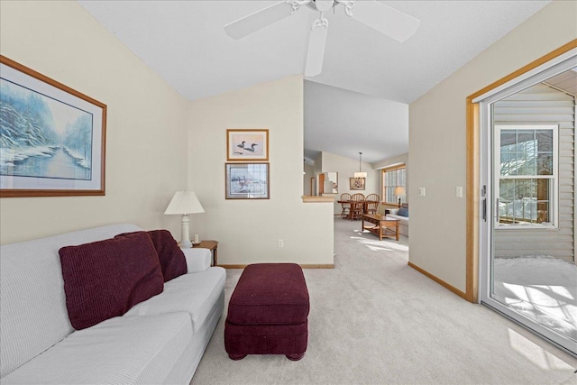 living area featuring light colored carpet, ceiling fan, baseboards, and vaulted ceiling