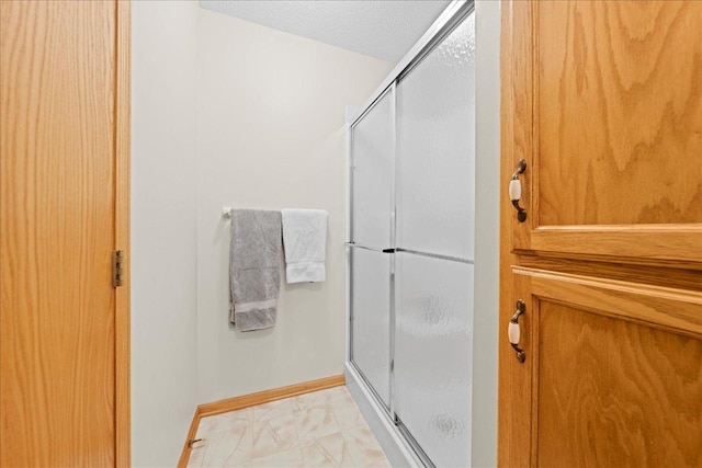 full bathroom with baseboards, a textured ceiling, and a stall shower