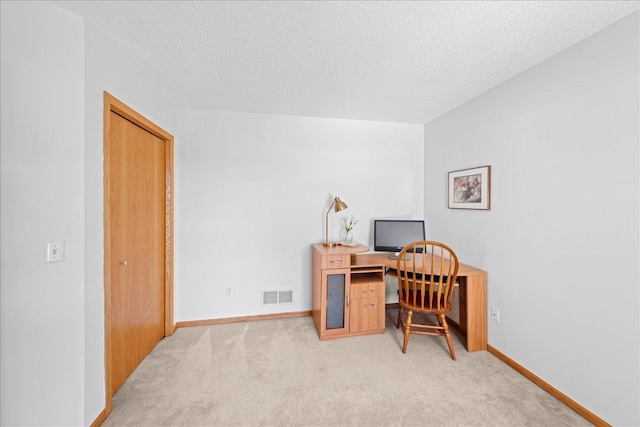 office featuring visible vents, baseboards, light colored carpet, and a textured ceiling