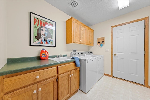 washroom with visible vents, washer and dryer, cabinet space, a textured ceiling, and a sink