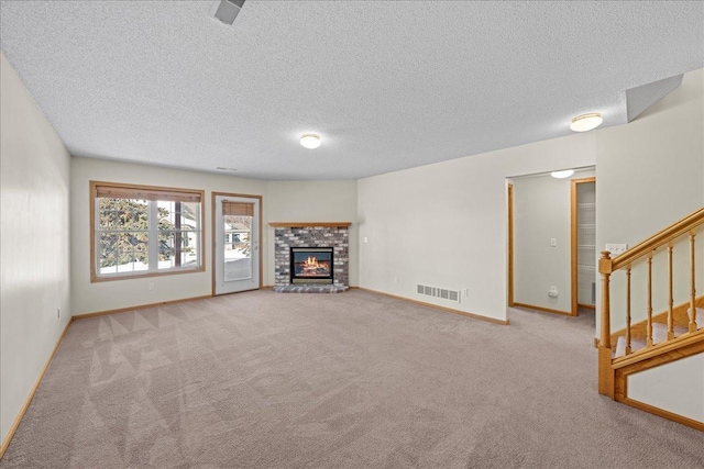 unfurnished living room featuring visible vents, carpet flooring, baseboards, a brick fireplace, and stairs