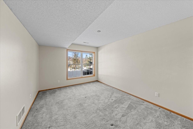 carpeted spare room featuring baseboards, visible vents, and a textured ceiling