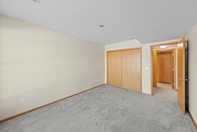 unfurnished bedroom featuring a closet, a textured ceiling, baseboards, and carpet