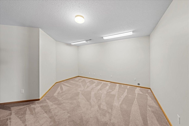 carpeted spare room featuring baseboards and a textured ceiling