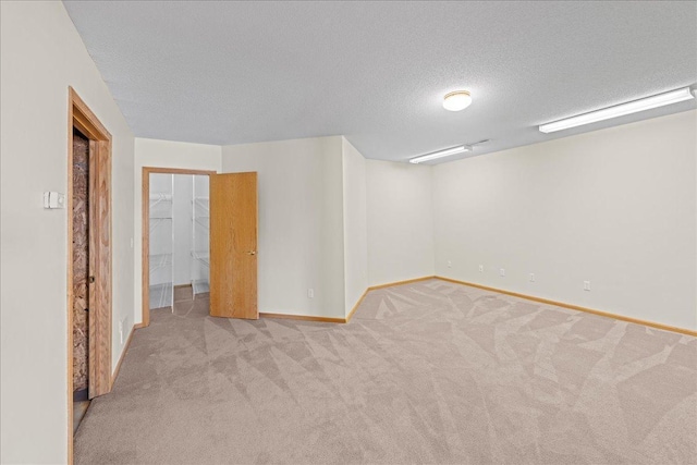 spare room featuring a textured ceiling, baseboards, and carpet floors