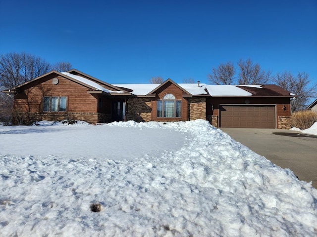 ranch-style house featuring an attached garage, stone siding, and driveway