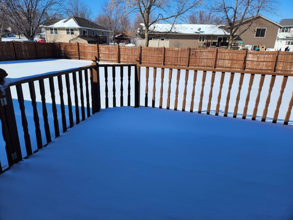 snowy yard with a residential view and a fenced backyard