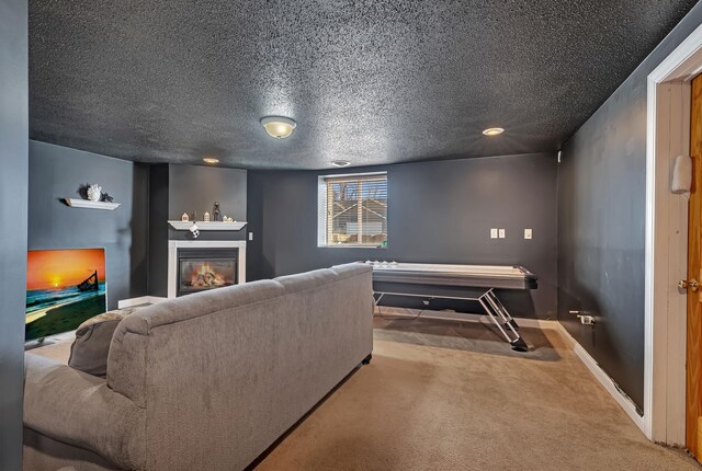 carpeted living area featuring a glass covered fireplace, a textured ceiling, and baseboards