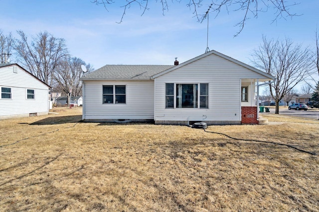 rear view of house with a yard and roof with shingles