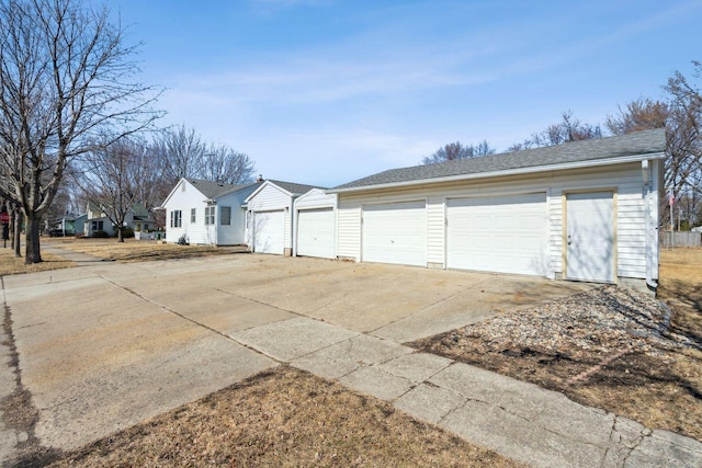 view of front of house with concrete driveway, a garage, and roof with shingles