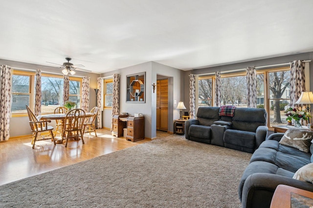 living room with a wealth of natural light, a ceiling fan, baseboards, and wood finished floors