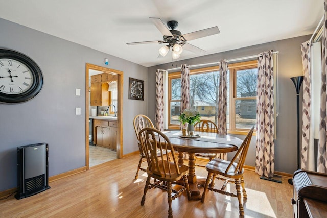 dining room with a ceiling fan, baseboards, and light wood-type flooring