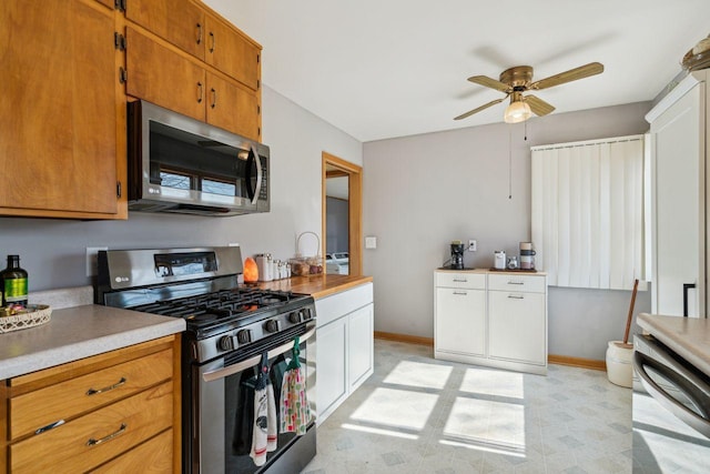 kitchen with brown cabinets, stainless steel appliances, light countertops, and baseboards