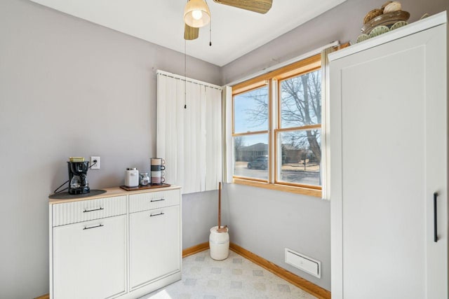 interior space featuring a ceiling fan, light floors, and baseboards