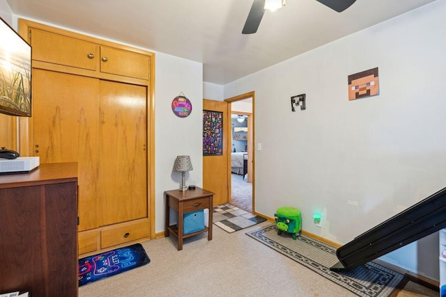 interior space with light colored carpet, baseboards, and ceiling fan