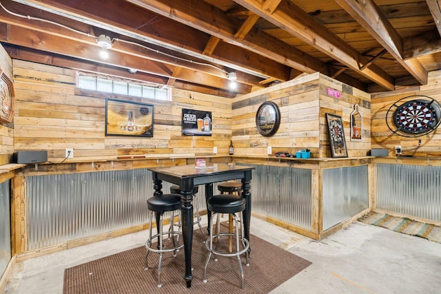 bar featuring unfinished concrete floors, wooden walls, and a dry bar