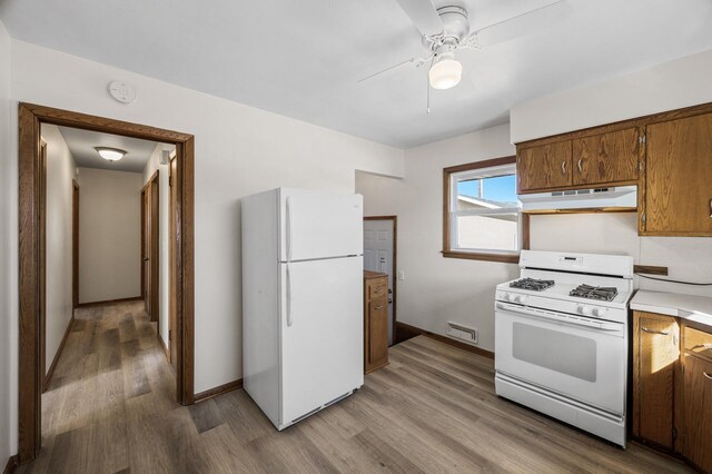 kitchen with visible vents, light wood finished floors, under cabinet range hood, white appliances, and light countertops