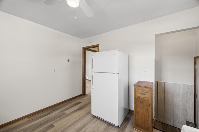 kitchen featuring light wood finished floors, ceiling fan, freestanding refrigerator, and baseboards