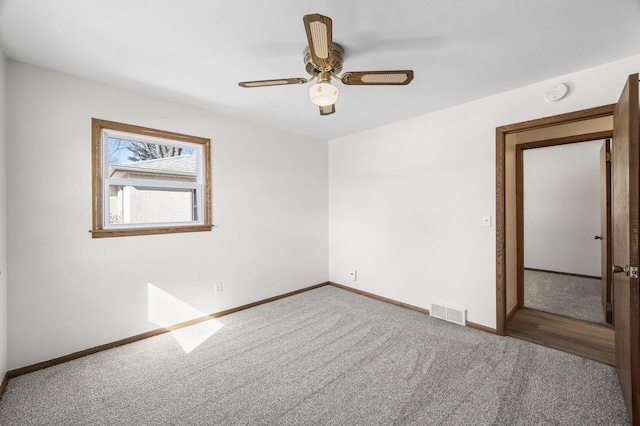 unfurnished room with visible vents, carpet flooring, baseboards, and ceiling fan