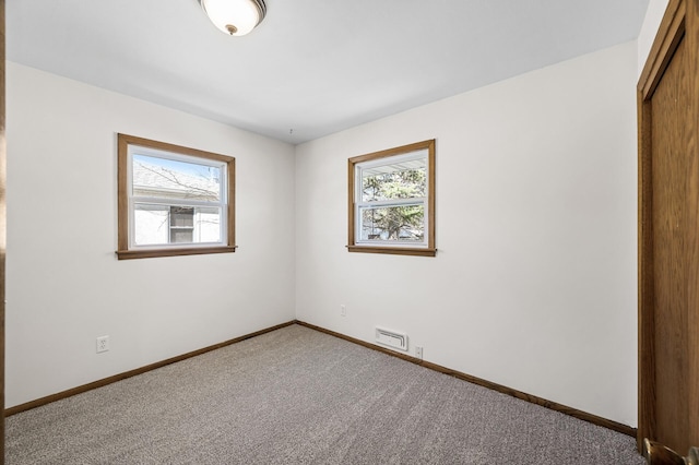 empty room featuring carpet, visible vents, a healthy amount of sunlight, and baseboards