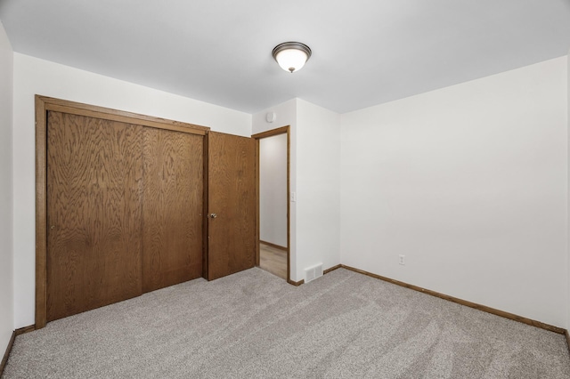 unfurnished bedroom with carpet flooring, baseboards, visible vents, and a closet