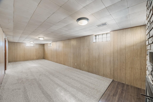 basement with visible vents, carpet floors, and wooden walls