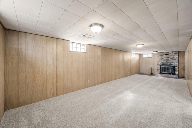 basement with wooden walls, a fireplace, carpet, and visible vents