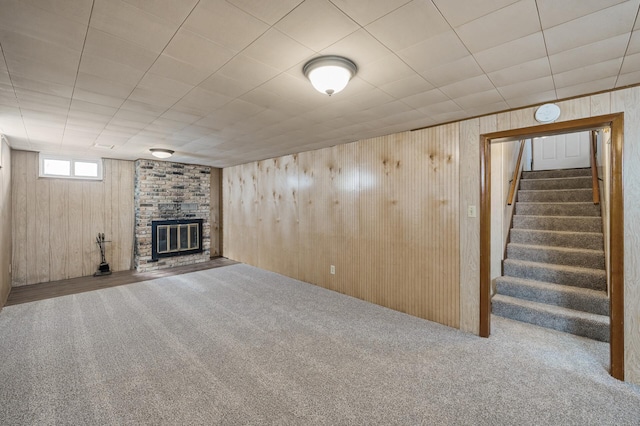 basement with a brick fireplace, stairway, wooden walls, and carpet