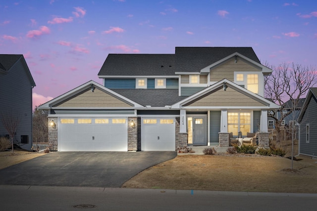 view of front facade with driveway, stone siding, a porch, a shingled roof, and a garage