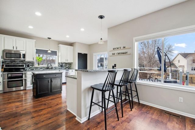 kitchen with dark wood-style floors, visible vents, a sink, stainless steel appliances, and tasteful backsplash