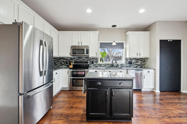 kitchen with dark wood-type flooring, a sink, appliances with stainless steel finishes, white cabinets, and light stone countertops