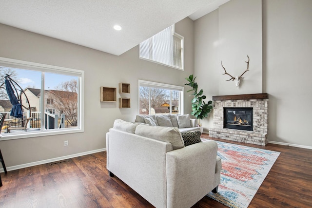 living room featuring visible vents, a brick fireplace, baseboards, and wood finished floors